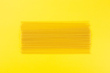 Raw spaghetti on yellow background