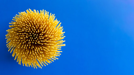 Bouquet of raw spaghetti on blue surface
