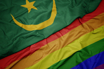 waving colorful gay rainbow flag and national flag of mauritania.