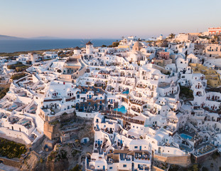 Aerial view of Santorini island, Greece, Oia village with windmills and white houses. Amazing sunset view of romantic island from quadcopter.The most romantic place for a wedding.