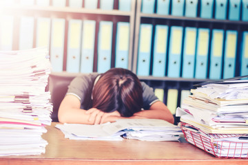 Blurred Business woman asleep on office desk at office desk with f paperwork stack documents and...