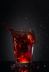 Cola glass with lemon and falling ice cubes.