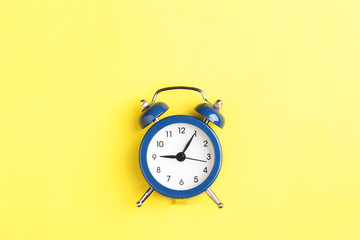 Alarm clock on yellow background.