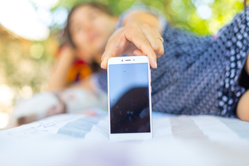 a young woman lies on a bed and photographs herself on the phone. Cheerful attractive woman in a blue pea shirt posing for a selfie. Social media concept