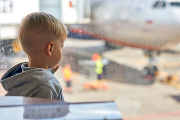 Two year old boy at the airport looking at plane