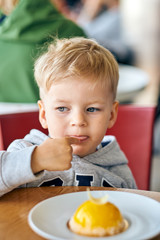 Two year old boy eating dessert in cafe