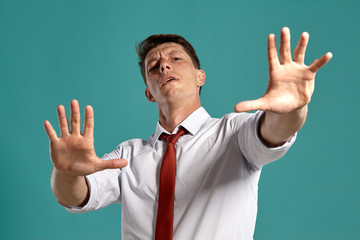 Young man in a classic white shirt and red tie posing over a blue background.