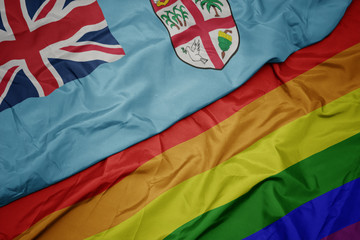 waving colorful gay rainbow flag and national flag of Fiji.