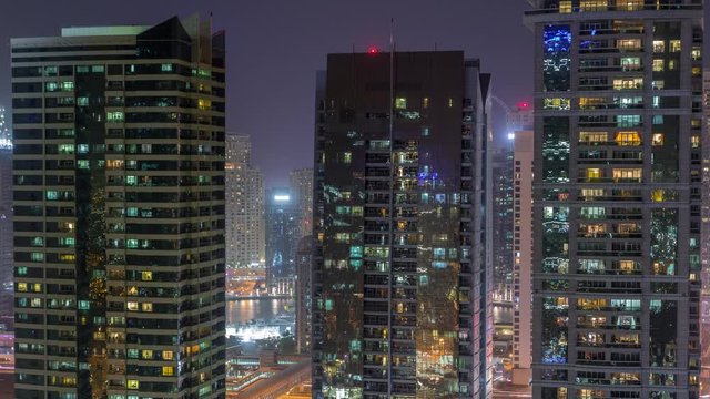 Residential and office buildings in Jumeirah lake towers district night timelapse with blinking lights in windows in Dubai. Aerial view from above with modern skyscrapers
