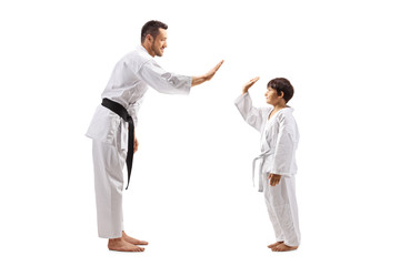 Boy and man in karate kimonos gesturing high-five