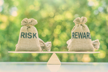 Risk reward ratio / risk management concept : Risk and reward bags on a basic balance scale in...