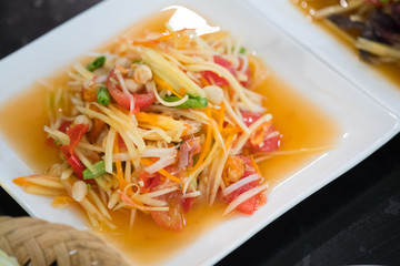 Papaya salad with tomato, shrimp, chili and bean on white plate