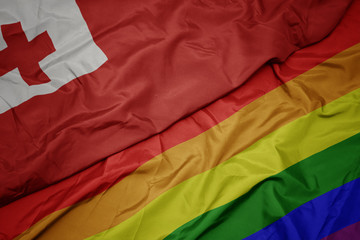 waving colorful gay rainbow flag and national flag of Tonga.