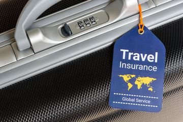 Fototapeta Travel insurance and travel security concept : Top view of travel insurance tag tied on a black suitcase holder near a numeric combination lock. Travel insurance is intended to cover lost luggage. obraz