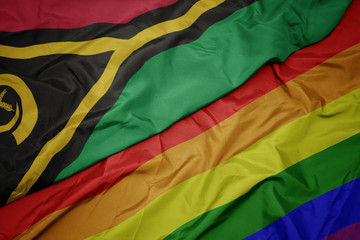 waving colorful gay rainbow flag and national flag of Vanuatu.
