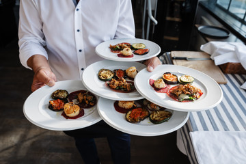 waiter serves Italian antipasti in an outdoor restaurant