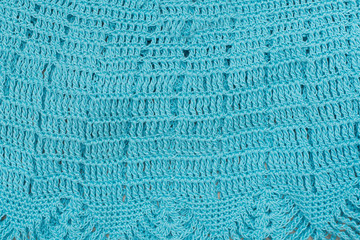 Knitted openwork pattern, turquoise color. Textured fabric. Handmade