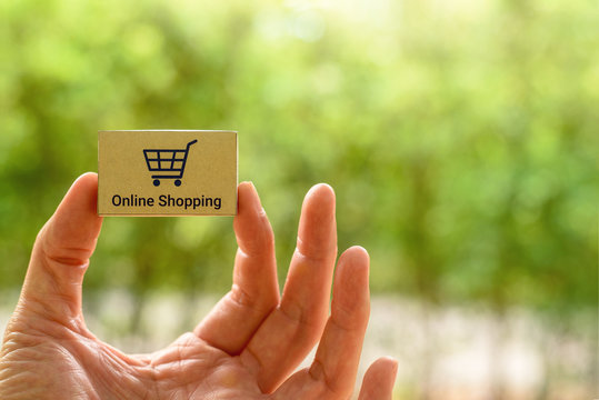 Internet or online shopping, e-commerce and free delivery service concept : Shopper or buyer / consumer picks or shows small box with a blue shopping cart logo, depicts buying products via cyber store