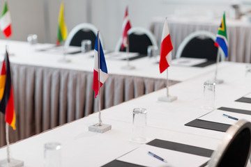 business, corporate and interior concept - table with flags and paper in boardroom at international conference