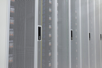 Close-up of a white metal grid cabinet with neatly arranged data centers