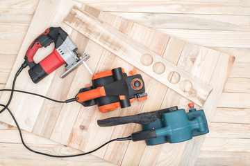 Set of handheld woodworking power tools for woodworking and the workpiece lies on a light wooden...