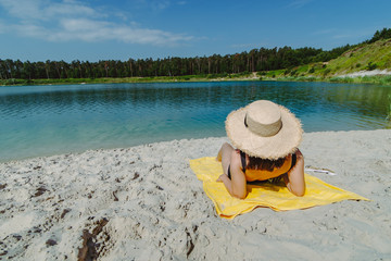 Fototapeta na wymiar woman laying on yellow blanket sunbathing at sand beach