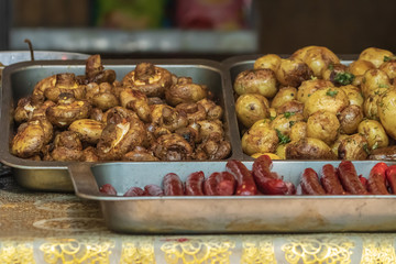 Culinary buffet with the presentation of healthy food - mushrooms, potatoes, sausages, peppers, spices, grilled vegetables. Food market, festival, event. The kitchen is outdoors. Street fair stand.