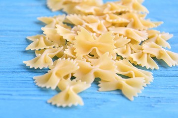 Traditional italian farfalle pasta with selective focus on blue textured wooden background. Bow tie noodles on wood backdrop. Raw organic farfalle noodle. Uncooked dried homemade farfalle. Butterfly 