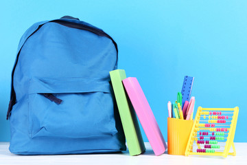 Backpack with school supplies on blue background