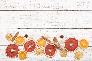 Dried citrus fruits with cinnamon, star anise and sugar cubes on white wooden table