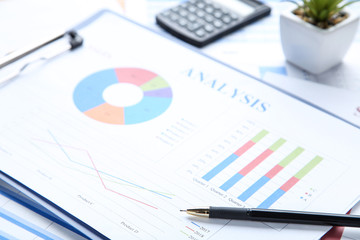 Financial graph and charts on clipboard with pen and calculator