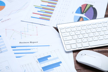 Financial papers graph, charts with keyboard and mouse on wooden table