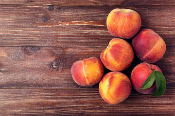 Fresh peaches with green leafs on brown wooden table