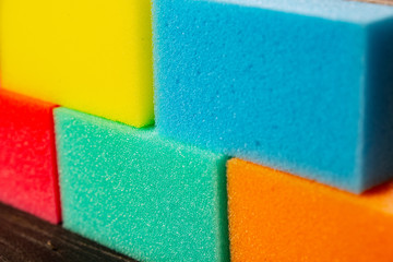 Sponges of different colors in dark background forming a wall. Pieces of dishcloth laid as bricks...