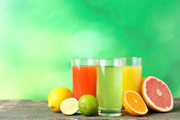 Citrus juice in glasses with fruits on green background