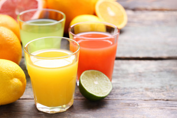 Citrus juice in glasses with fruits on grey wooden table