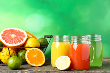Fototapeta na wymiar Citrus juice in glass jars with fruits on green background