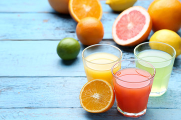 Citrus juice in glasses with fruits on blue wooden table