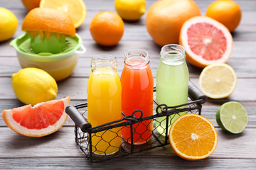 Citrus juice in glass bottles with fruits on wooden table