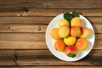 Sweet apricots in plate on brown wooden table