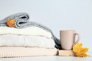 Folded sweaters with cup and maple leafs on grey background