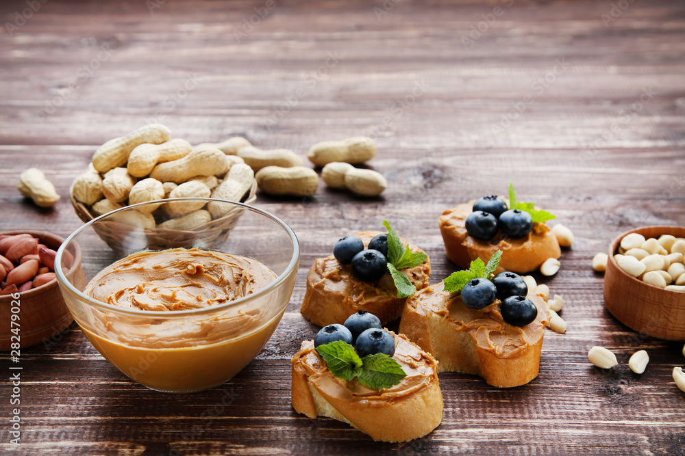 Poster Bread with peanut butter, blueberries and nuts on wooden table