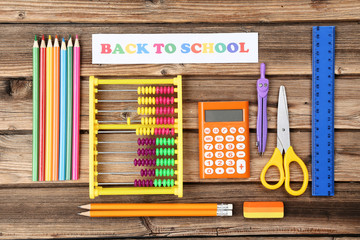Text Back To School with stationery on brown wooden table