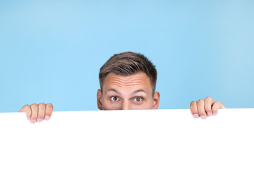 Young man with blank board on blue background