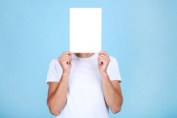 Young man with blank board on blue background
