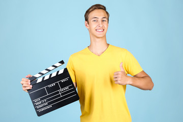 Young man with clapper board on blue background