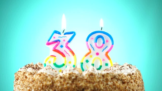 Birthday cake with a burning birthday candle. Number 38 Background changes color