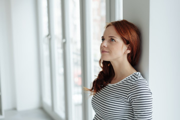 Thoughtful young woman standing daydreaming