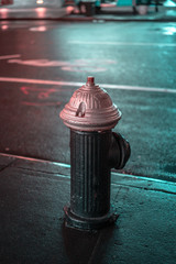 A water hydrant painted black and purple in the street at night