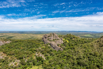 Fototapeta na wymiar Beautiful aerial view of Serra do Cipo in Minas Gerais with forests and rock mountains in sunny summer day with blue sky. Landscape of the Brazilian Cerrado, one of the most devastated biomes.